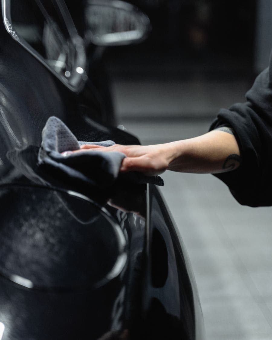 Mano secando con microfibra la pintura de un carro negro